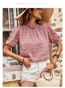 Dettaglio della camicetta rosa con texture Swiss Dot e collo alto a balze eleganti