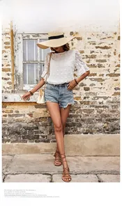 Outdoor summer scene of white chiffon blouse with ruffle sleeves and denim shorts