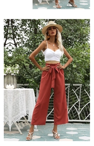 Détail du pantalon large taille haute rouge brique avec un nœud décoratif à la taille