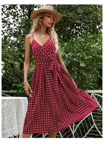 Detailed view of women's red polka dot dress featuring a V-neck and pleated skirt