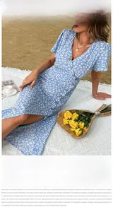 Détail de robe fleurie bleu clair avec col en V et boutons sur une plage d'été