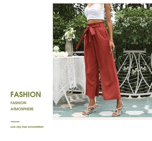 Détail du pantalon large taille haute orange brûlé avec taille paperbag et ceinture