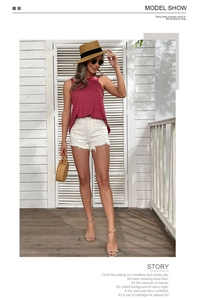 Detail view of burgundy halter top and white denim shorts for a summer vacation look