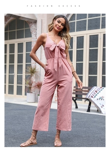 Detailed close-up of pink linen jumpsuit featuring a large bow tie and gathered waist