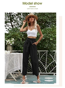 Détail du pantalon noir à taille haute et jambes larges avec ceinture plissée et poches