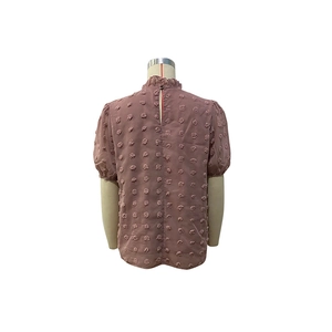 Dettaglio della camicetta di chiffon rosa con tessuto a pompon e chiusura sul retro