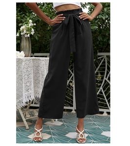Détail du pantalon noir à taille haute et jambes larges avec ceinture à nouer