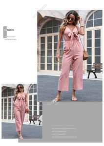 Detail of pink cotton linen jumpsuit with deep V-neck, waist bow, and wide-leg design