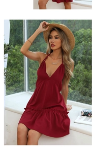 Detail of burgundy V-neck halter dress with ruffled hem and Gemini necklace accent