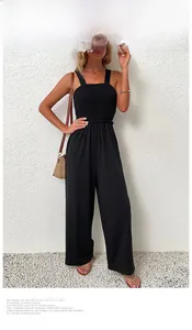 Detail eines schwarzen Jumpsuits mit Smok-Oberteil und weitem Bein an einem Model am Strand
