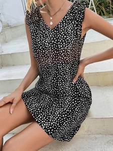 Detail of V-neck and ruffle shoulder straps on a black polka dot summer dress