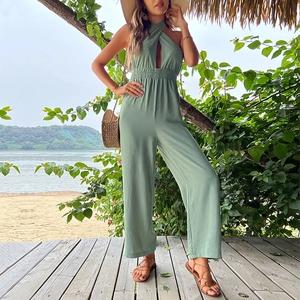 Salbeigrüner Neckholder-Jumpsuit mit Cut-out-Detail und weitem Bein in tropischer Umgebung