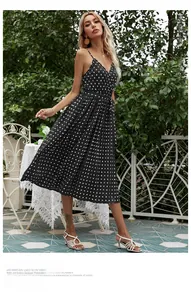 Polka dot V-neck midi dress with pleated skirt and waist tie shown in a garden