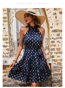 Detail of navy halter neck dress featuring golden leaf print and tiered ruffle hemline
