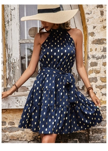 Detail view of navy blue tiered dress with golden polka dots and halter neck design