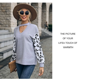 Detail of grey knit sweater with leopard print sleeves and a cutout V-neck design