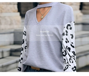 Detail of grey waffle knit top featuring leopard print patchwork sleeves and cutout V-neck