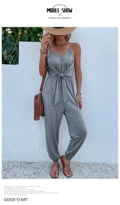 Detail of grey V-neck jumpsuit featuring waist tie-knot and stylish jogger cuffs