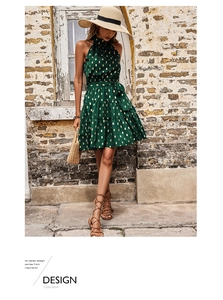 Detail of deep green halter neck dress with gold polka dots and ruffled hemline