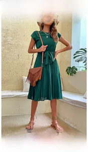 Detail of dark green pleated dress featuring a round neck and waist tie ribbon design