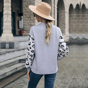 Women's casual grey knit top with leopard print patchwork sleeves on casual street setting