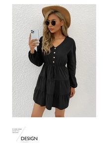 Close-up of black V-neck dress with wood-style buttons and layered ruffle hem detailing