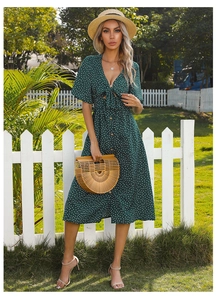 Detail of dark green polka dot dress featuring V-neckline and decorative front bow tie
