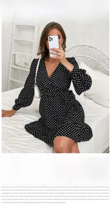 Close-up detail of the deep V-neck wrap design and waistline on this black polka dot dress