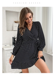 Detail of black polka dot V-neck dress featuring long sleeves and tie waist detail