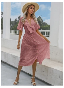 Detailed view of pink polka dot midi dress with V-neck, bow detail, and button-up front