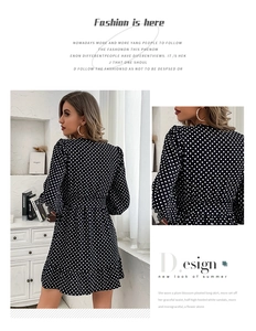 Detail view of the ruffle hem and polka dot pattern on a black long sleeve mini dress