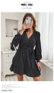 Detail of a black polka dot wrap dress featuring long sleeves and a waist tie closure