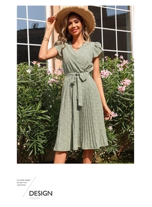 Détail de robe d'été fleurie verte avec col en V croisé et ourlet de jupe plissé