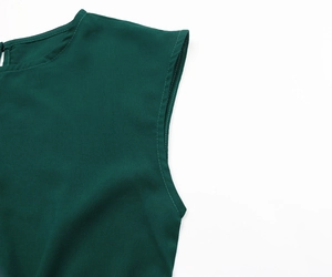 Close-up of the crew neck, rear button closure, and refined stitching on a dark green dress
