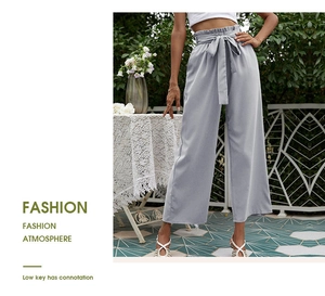 Détail d'un pantalon large taille haute gris clair avec une ceinture à nœud élégante
