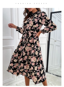 Détail d'une robe fleurie en mousseline avec roses, col évidé et jupe à plusieurs niveaux