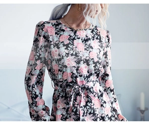 Détail d'une robe fleurie à manches longues montrant le motif rose et la ceinture en tissu
