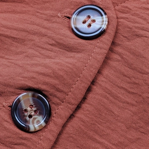 Vista macro del tessuto crepe ruggine con bottoni marmorizzati sulla tuta a gamba larga