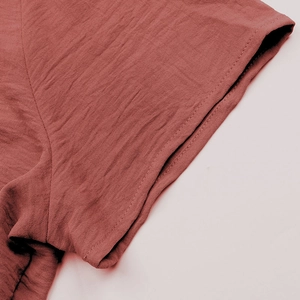 Dettaglio della doppia cucitura sul polsino in tessuto rosso mattone e trama materiale