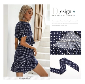 Detail view of navy polka dot summer dress showing elastic waist and ruffle hem design