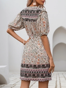 Detail view of the back of a floral bohemian dress with puff sleeves and tassel trim