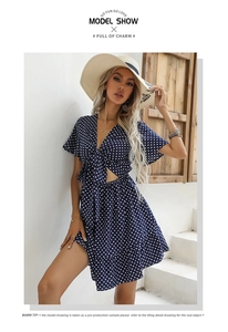 Close-up of V-neck tie detail and hollow waist cut-out on navy polka dot summer dress