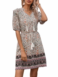 Detail of V-neckline with white tassels and floral print on bohemian summer dress
