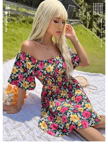 Détail d'une robe fleurie à épaules dénudées avec manches à volants sur l'herbe