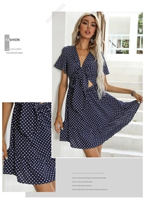 Detail of navy blue polka dot dress featuring V-neckline with tie and cutout design