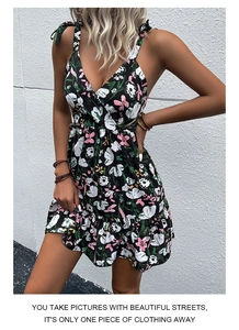 Detail of floral mini dress with bow straps and ruffled hem against a white wall