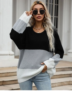 Close-up of color-block knit sweater texture with neutral black, grey, and white stripes