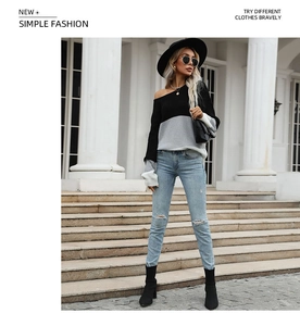 Detail of black and grey patchwork knit sweater with off-shoulder design and ribbed cuffs