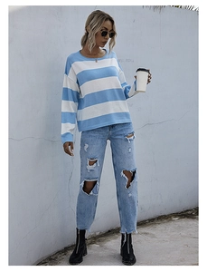 Stile street di una donna con un maglione a righe blu e bianche con girocollo e jeans denim