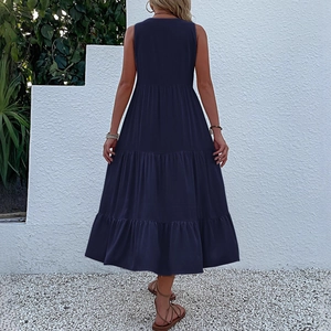 Deep blue sleeveless tiered maxi dress with V-neckline in a relaxed outdoor summer setting